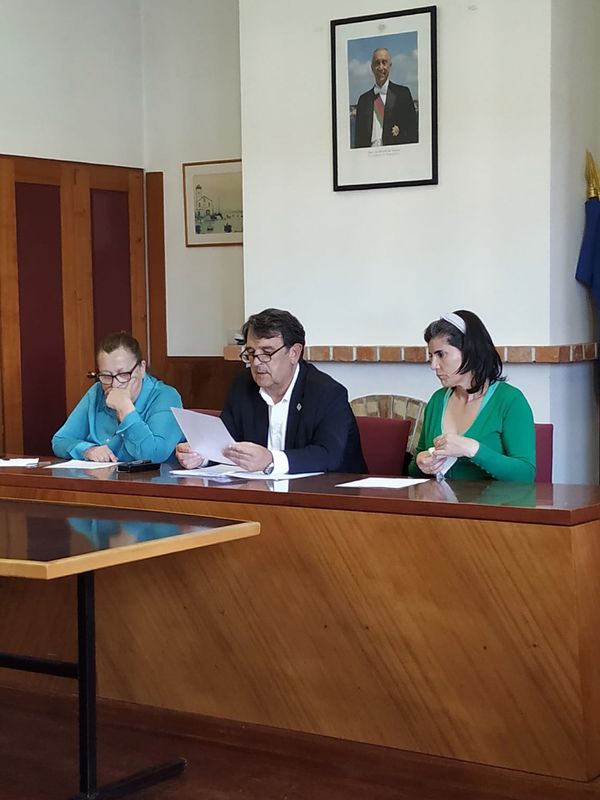 três pessoas, uma a ler uma papel