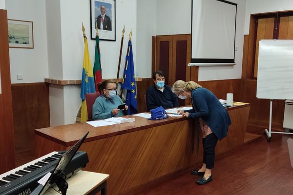 três pessoas, uma a assinar um papel