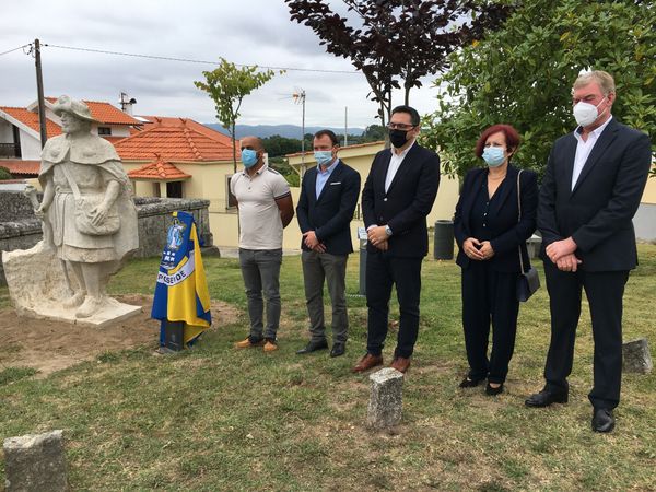 cinco pessoas num parque ao lado duma estátua de pedra