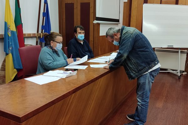 três pessoas, uma a assinar um papel