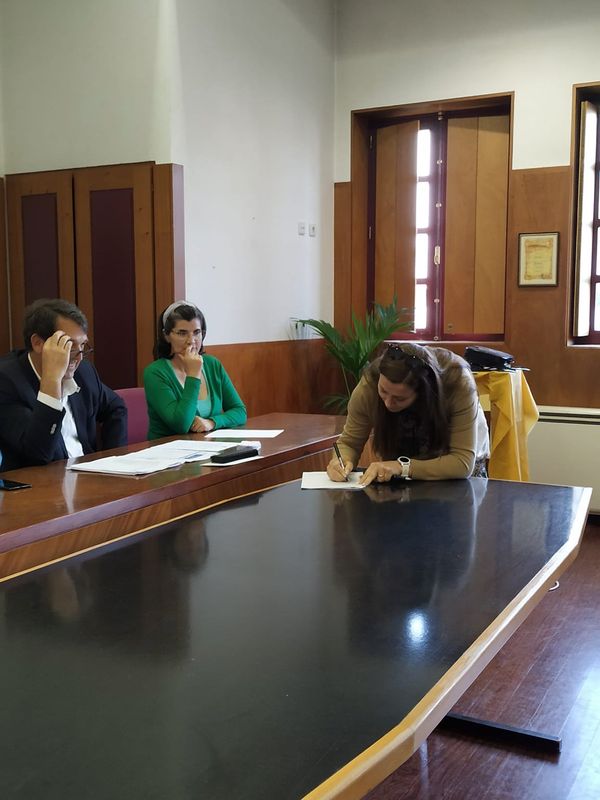 três pessoas, uma a assinar um papel