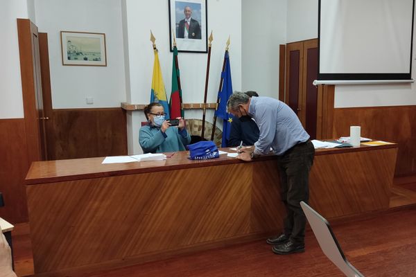 três pessoas, uma a assinar um papel