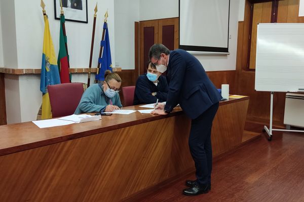 três pessoas, uma a assinar um papel