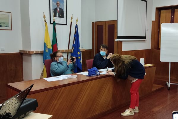 três pessoas, uma a assinar um papel