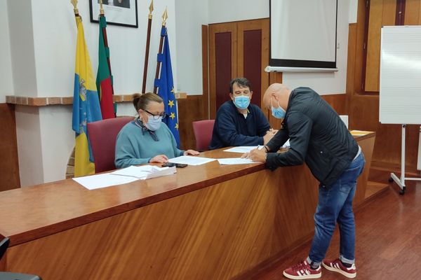 três pessoas, uma a assinar um papel