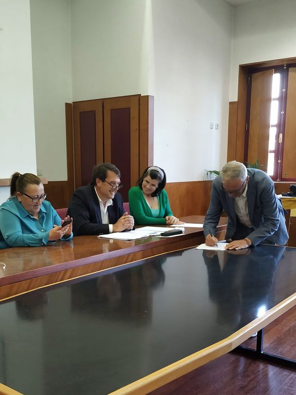 três pessoas, uma a assinar um papel