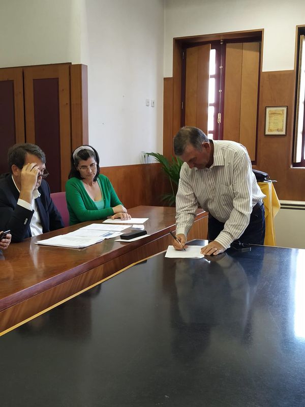 três pessoas, uma a assinar um papel